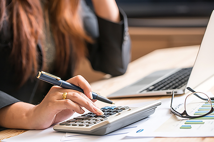 lady working at desk with hand on calculator